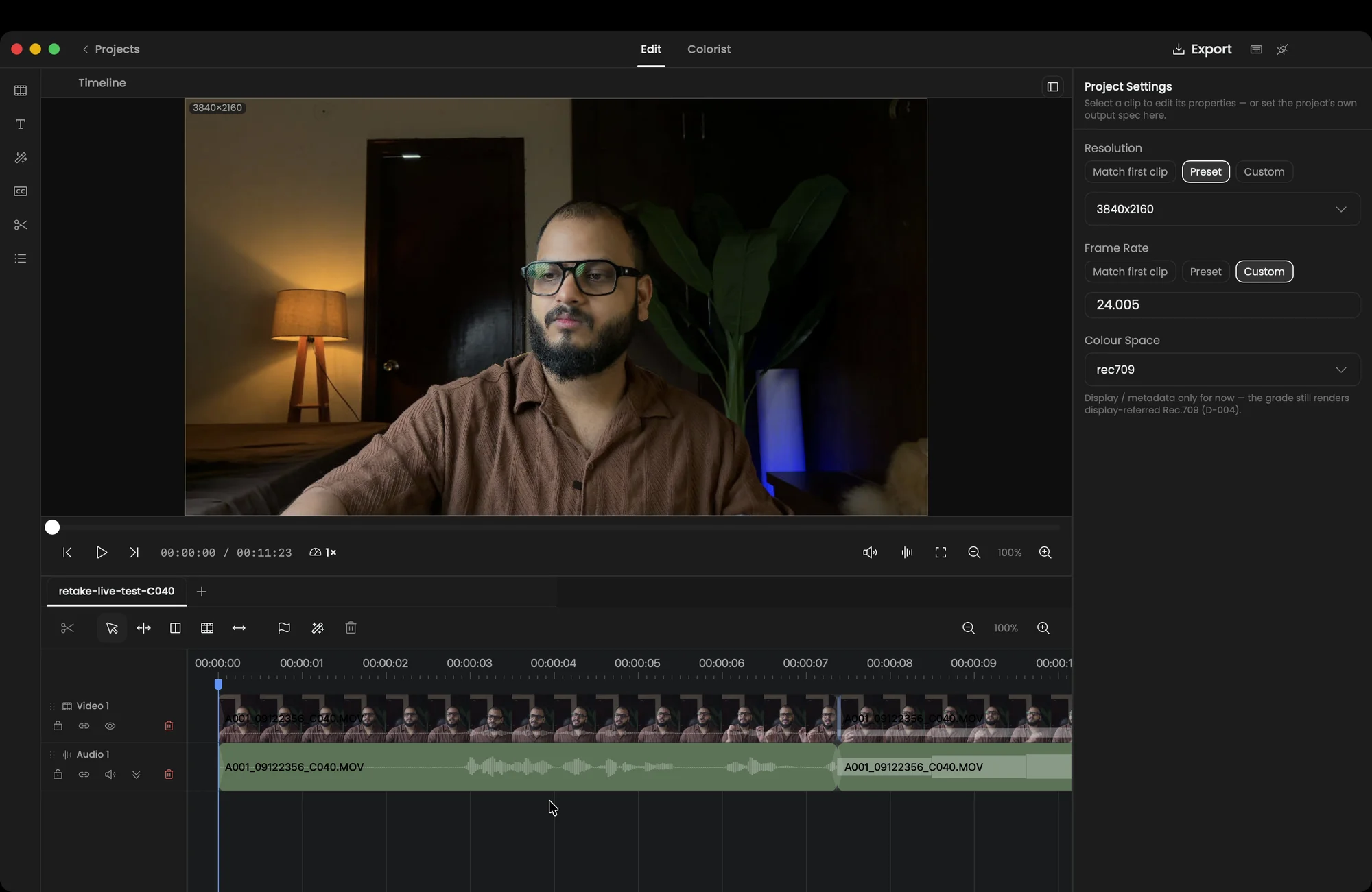 The Apelles Edit room: a 4K talking-head clip in the preview, the Project Settings inspector on the right, and a two-track timeline below with a real filmstrip and audio waveform, split at a cut.
